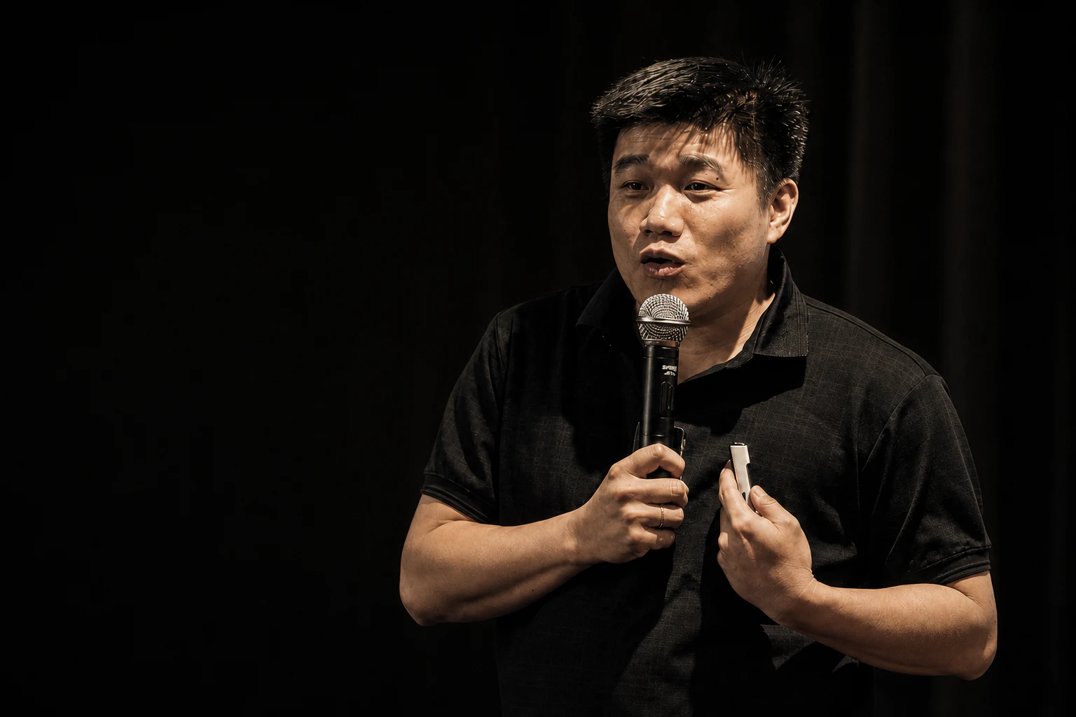Thông Phan đang cầm micro chia sẻ trên sân khấu.